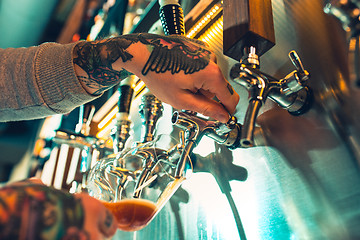 Image showing Hand of bartender pouring a large lager beer in tap.