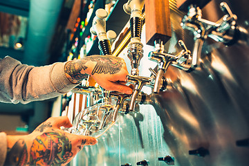 Image showing Hand of bartender pouring a large lager beer in tap.