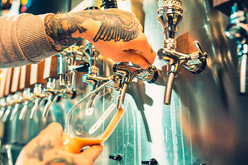 Image showing Hand of bartender pouring a large lager beer in tap.