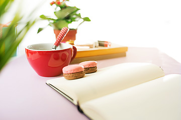 Image showing The side view on female desk. The phone and french macarons on trendy pink desk.