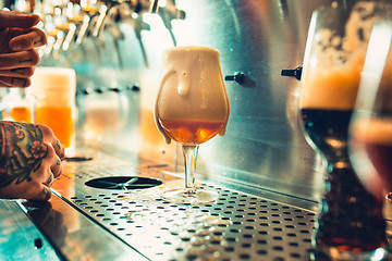 Image showing Hand of bartender pouring a large lager beer in tap.