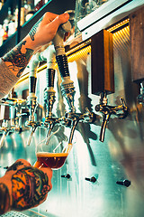 Image showing Hand of bartender pouring a large lager beer in tap.