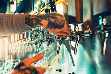 Image showing Hand of bartender pouring a large lager beer in tap.