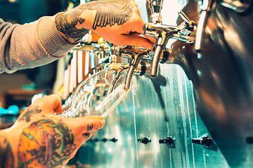 Image showing Hand of bartender pouring a large lager beer in tap.