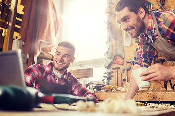 Image showing two smiling carpenters with laptop at workshop