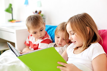Image showing little kids reading book in bed at home