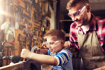 Image showing father and son with plane shaving wood at workshop