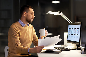 Image showing man with papers and computer works at night office