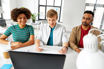 Image showing creative team looking at laptop papers at office