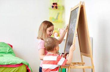 Image showing happy kids drawing on chalk board at home