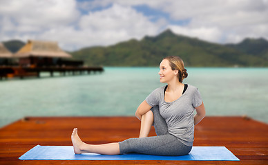 Image showing woman making yoga in twist pose on mat outdoors