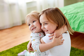 Image showing happy little girls or sisters hugging at home