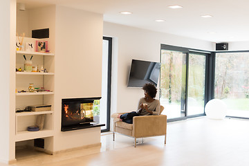 Image showing black woman drinking coffee in front of fireplace