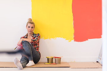 Image showing young female painter sitting on floor