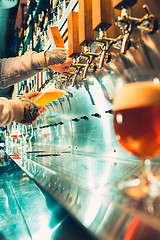 Image showing Hand of bartender pouring a large lager beer in tap.