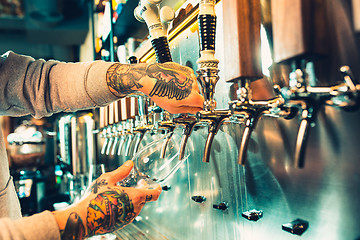 Image showing Hand of bartender pouring a large lager beer in tap.