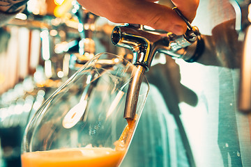 Image showing Hand of bartender pouring a large lager beer in tap.