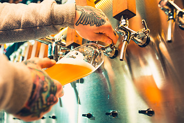 Image showing Hand of bartender pouring a large lager beer in tap.