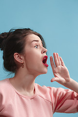 Image showing Isolated on blue young casual woman shouting at studio