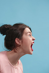 Image showing The young emotional angry woman screaming on blue studio background