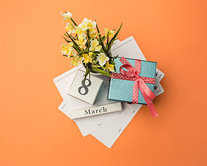 Image showing The top view of orange desk with gift, flowers and notebook
