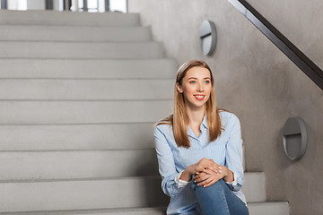 Image showing happy smiling woman or student sitting on stairs