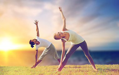Image showing couple making yoga triangle pose outdoors