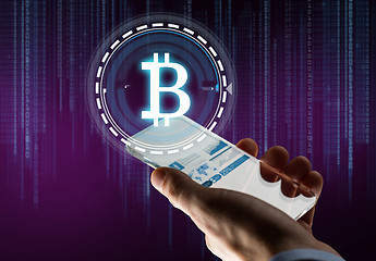 Image showing hand with smartphone and bitcoin hologram