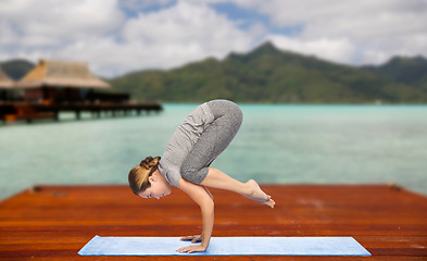 Image showing woman making yoga in crane pose on mat outdoors