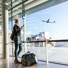 Image showing Young woman waiting at airport, looking through the gate window.