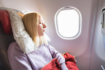 Image showing Tired blonde casual caucasian lady sleepin on seat while traveling by airplane. Commercial transportation by planes.