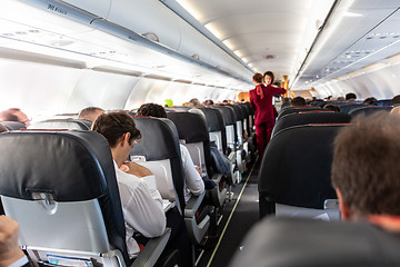 Image showing Interior of commercial airplane with passengers on their seats during flight.