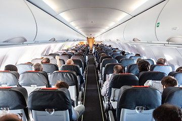 Image showing Interior of commercial airplane with passengers on their seats during flight.