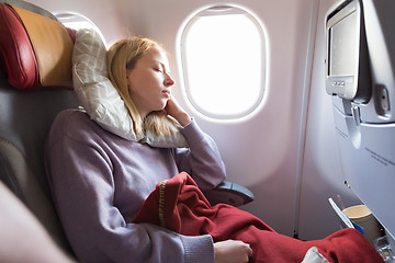 Image showing Tired blonde casual caucasian lady sleepin on seat while traveling by airplane. Commercial transportation by planes.