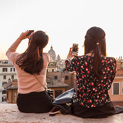 Image showing Female tourists taking mobile phone photos of Piazza di Spagna, landmark square with Spanish steps in Rome, Italy at sunset.