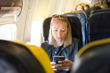 Image showing Woman using mobile phone as entertainment on airplane during commercial flight.