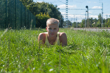 Image showing Young man in yellow t-shirt sitting on the green grass