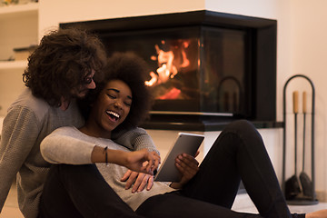 Image showing multiethnic couple using tablet computer on the floor