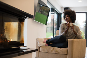 Image showing black woman drinking coffee in front of fireplace