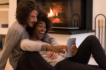 Image showing multiethnic couple using tablet computer on the floor