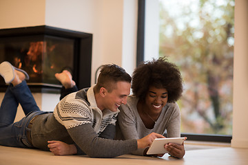 Image showing multiethnic couple using tablet computer on the floor