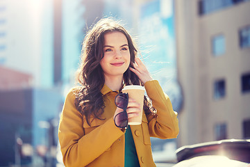 Image showing happy young woman drinking coffee on city street