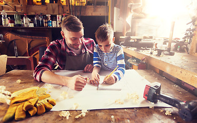 Image showing happy father and son with blueprint at workshop