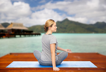 Image showing woman making yoga in twist pose on mat outdoors