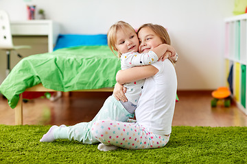 Image showing happy little girls or sisters hugging at home