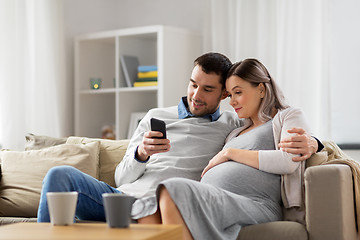 Image showing man and pregnant wife with smartphone at home