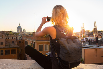 Image showing Female tourist taking mobile phone photo of Piazza di Spagna, landmark square with Spanish steps in Rome, Italy at sunset.