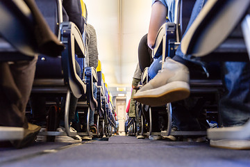 Image showing Low agle view of passenegers commercial airplane aisle with passenegers sitting on their seats while flying