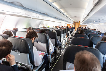 Image showing Interior of commercial airplane with passengers on their seats during flight.