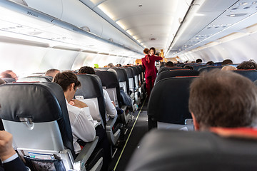 Image showing Interior of commercial airplane with passengers on their seats during flight.